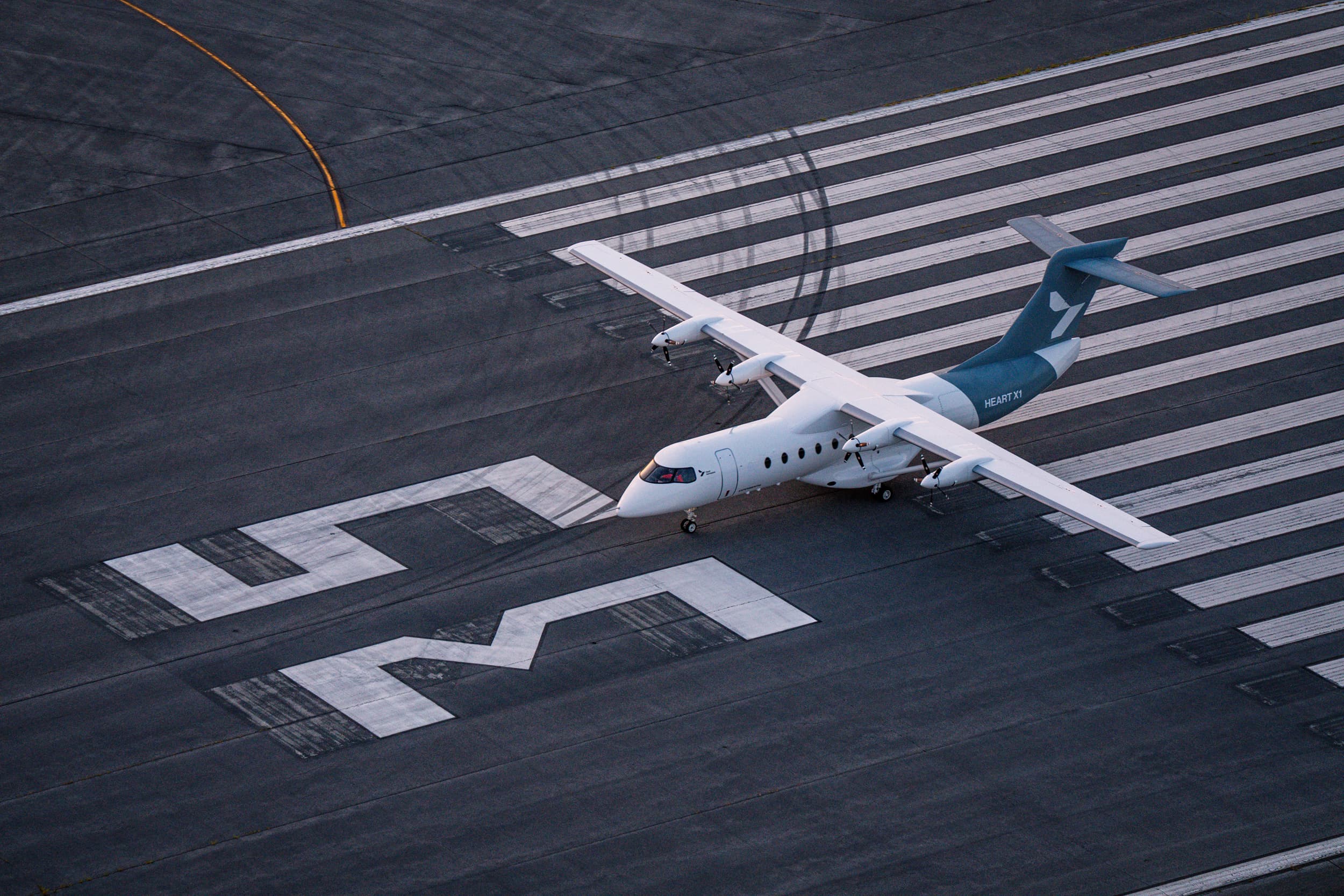 Aerial view of Heart Aerospace’s white, four-engine X1 electric demonstrator taxiing.