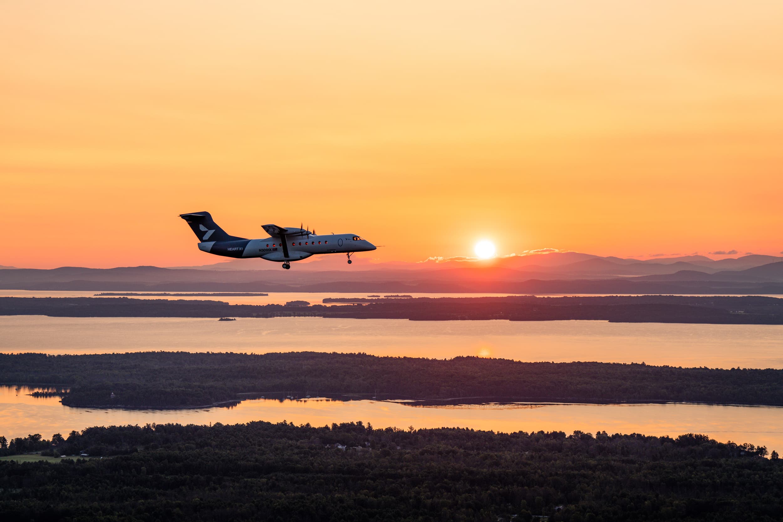 Heart Aerospace’s X1 electric demonstrator flies toward the rising sun above Lake Champlain.
